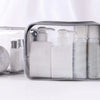 A clear waterproof travel cosmetic bag containing several white liquid bottles and a circular mirror.