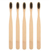 Four natural bamboo toothbrushes shown vertically in light wood tones