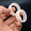 A hand holds three translucent silicone ear tunnel plugs, showing their size and shape.