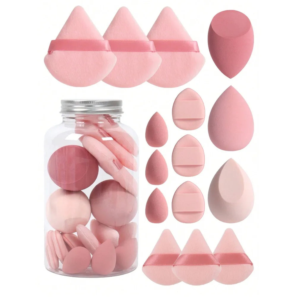 A collection of 15 pink makeup sponges in various shapes and sizes displayed next to a glass jar.