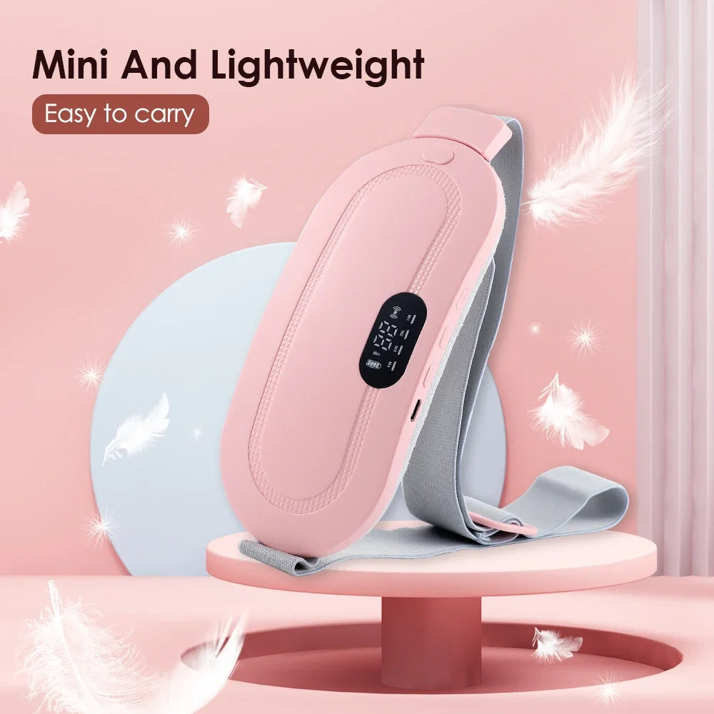 A pink electric massager belt is shown lying on a light pink stand with white feathers in the background.
