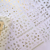 A close-up of gold star nail art stickers and decals for acrylic nails on a white background.