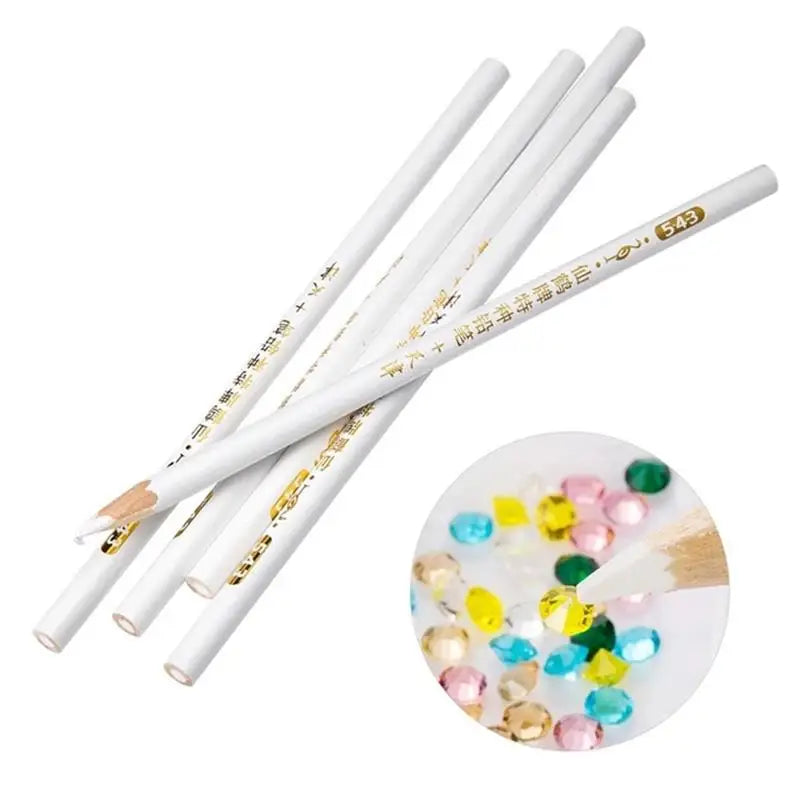 A set of white wax picker pencils with gold accents and a pile of colorful rhinestones.