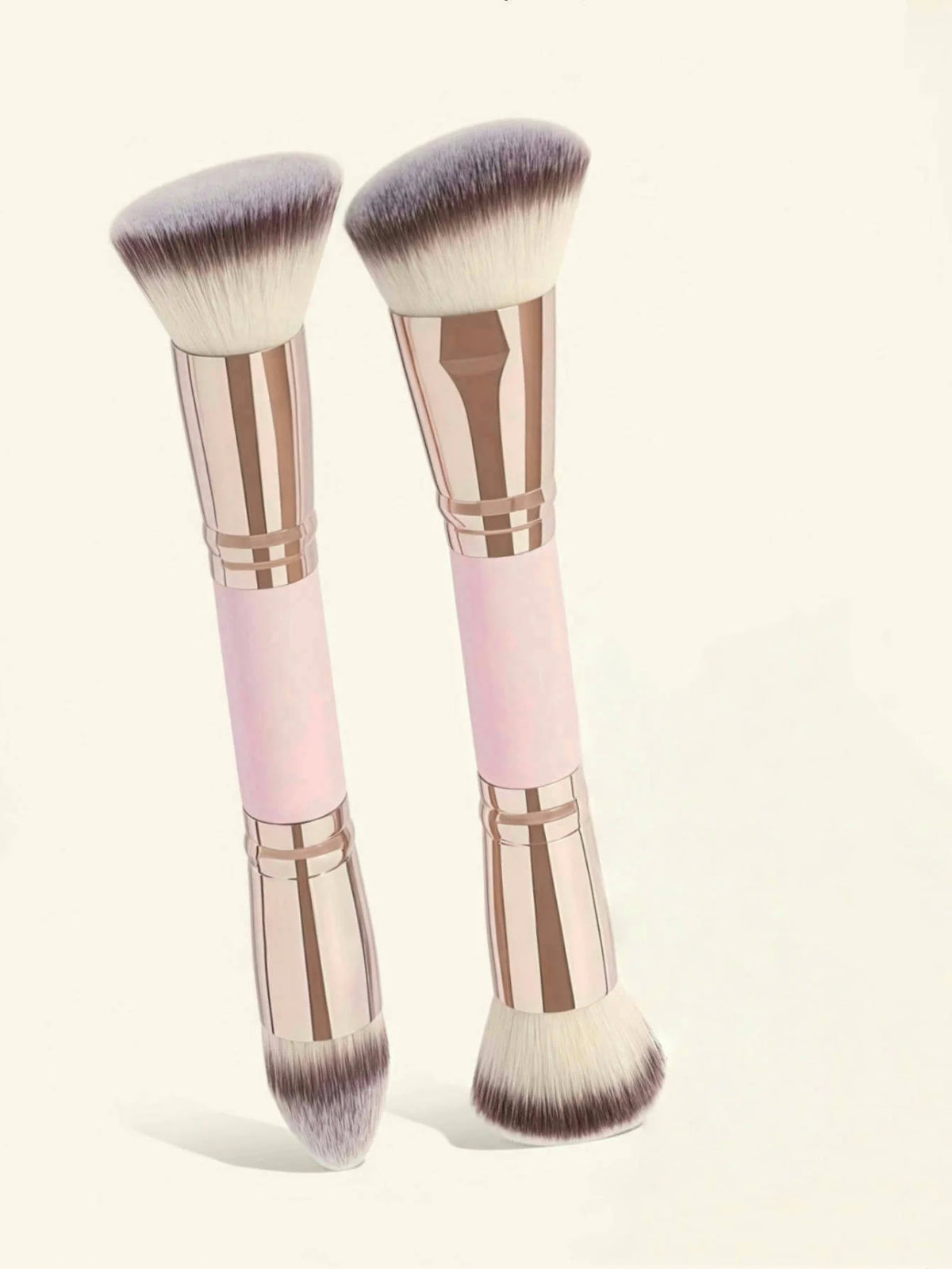 A pair of precision double-ended makeup foundation brushes with pink and rose gold handles and fluffy synthetic bristles.