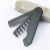 Peigne à cheveux gris foncé pliable à dents serrées posé sur une surface en bois.