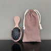 A set of matte boar bristle hair extension brushes in dusty rose color, shown against a gray background.