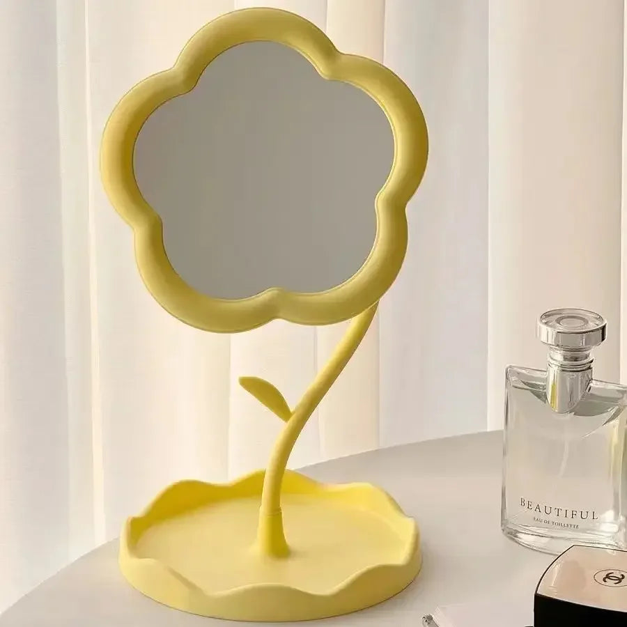 Miroir de fleur de bureau jaune avec cadre et tige incurvés, posé sur une surface blanche.