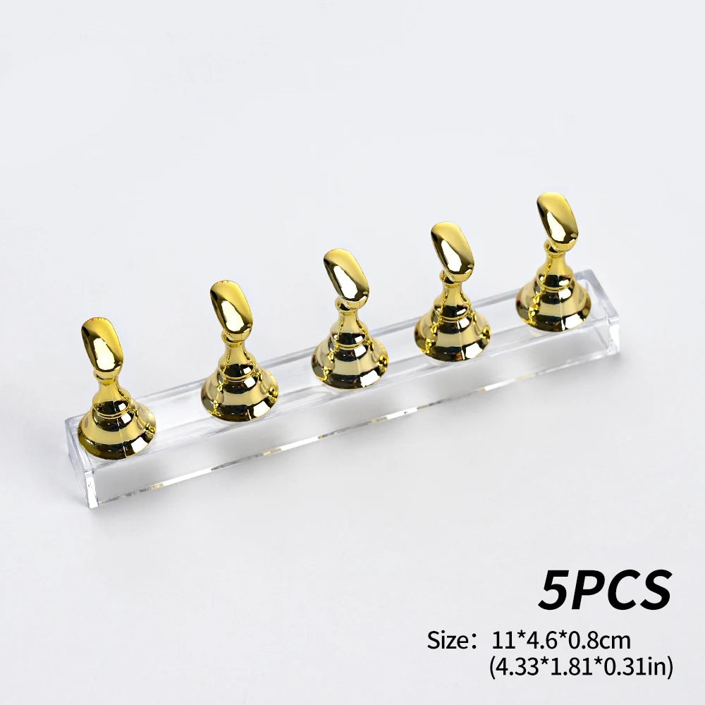 Un ensemble de cinq supports à ongles magnétiques dorés métalliques sur une base en acrylique transparent.