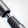 Close-up of a black electric hair trimmer with a magnetic cutter head protective cover and a hidden switch.