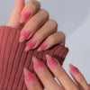 A hand models almond press-on nails with a pink bow design on a medium length set.