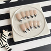 Un set de uñas postizas de rayas de cebra beige y negro, exhibidas en un plato de cerámica blanca.