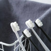 A close-up of a set of white and black ultra-fine bristle toothbrushes resting on a gray towel.