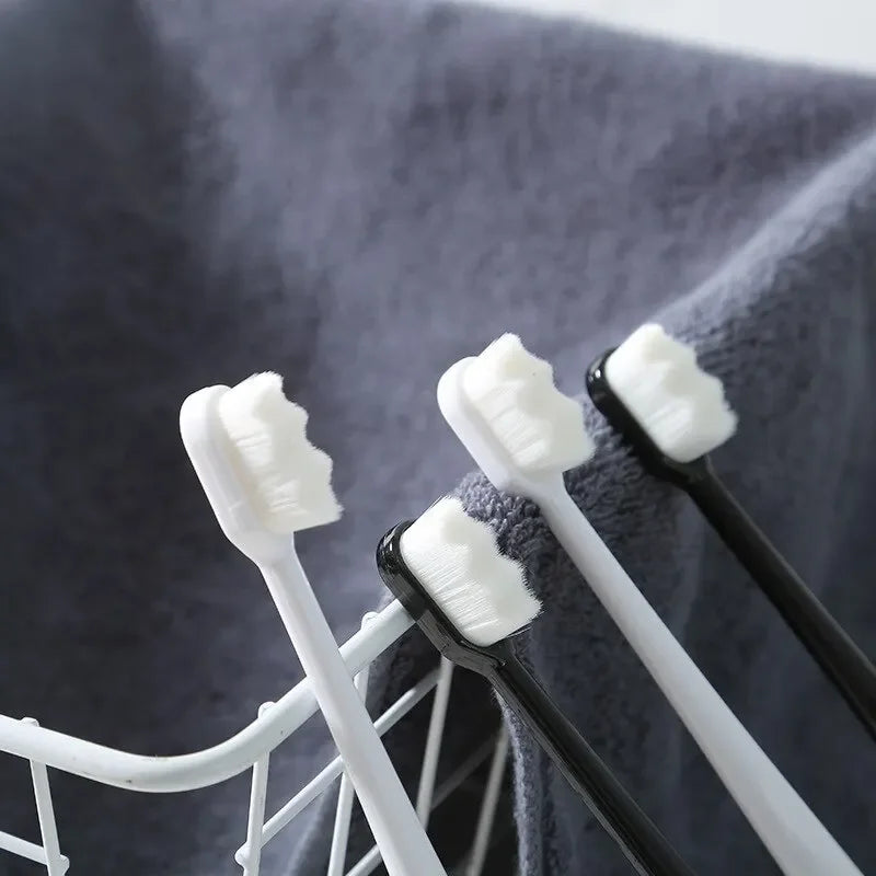 A close-up of a set of white and black ultra-fine bristle toothbrushes resting on a gray towel.