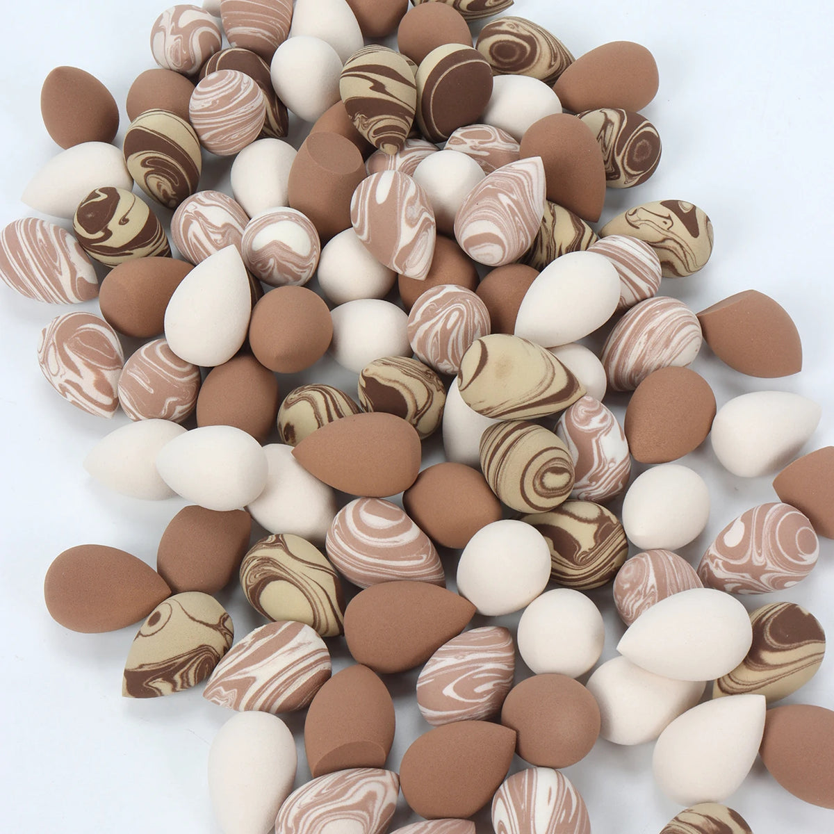A collection of reusable expandable makeup sponges in various natural and earthy tones.