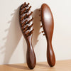 A wooden massage comb with rounded teeth is shown against a light background.