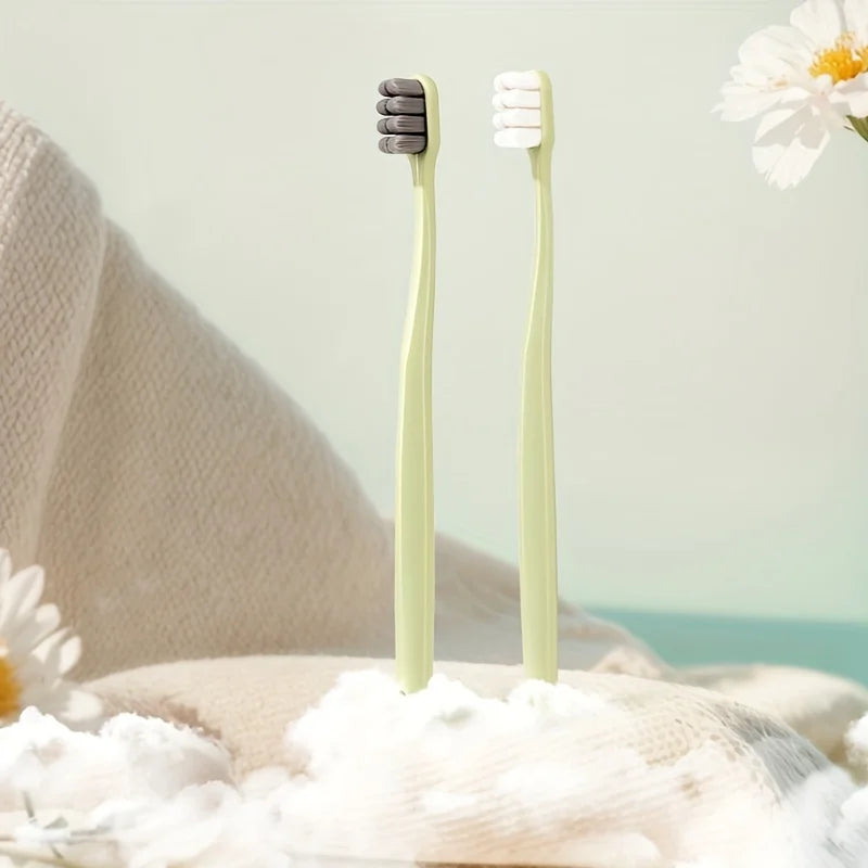 Une paire de brosses à dents micro-nano vert clair posées sur une serviette beige douce avec de la peluche blanche.