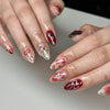 Close-up of hands displaying pink heart pearl press-on fake nails with various designs and finishes.