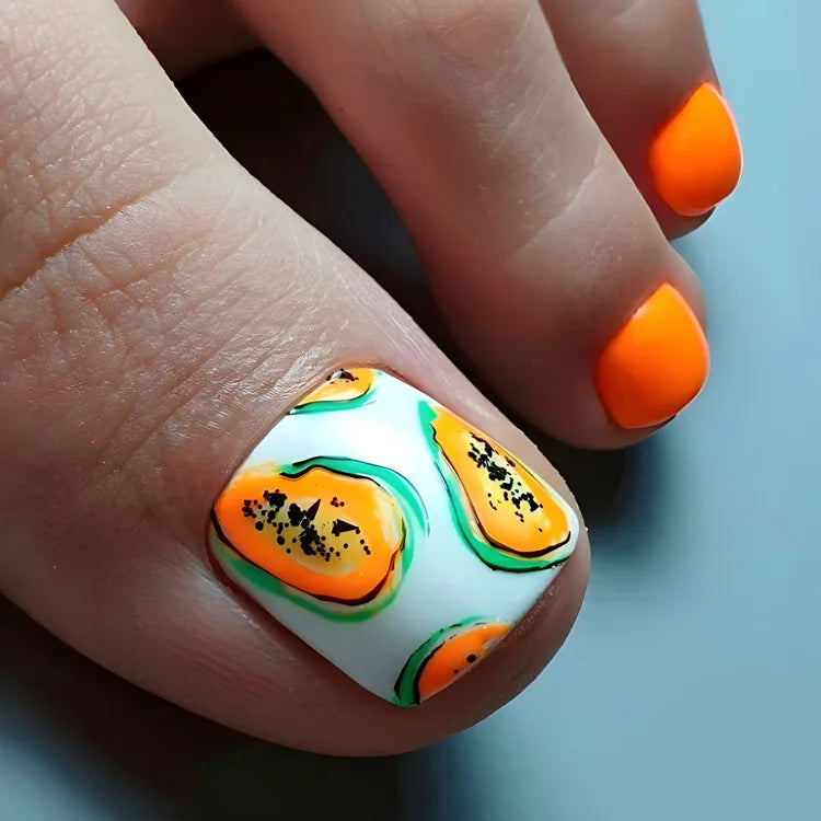 Nahaufnahme einer Hand, die wiederverwendbare französische Kunstnagel mit orange-grünen Akzenten zeigt.