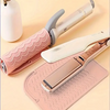 A pink silicone heat resistant mat is shown with a hair styling tool and its cleaning brush on a light background.