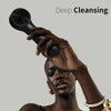 A person is using a black silicone facial cleansing brush on their face for deep cleansing.