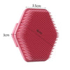A pink silicone facial cleaning and massage brush with ridges and a hexagonal shape.