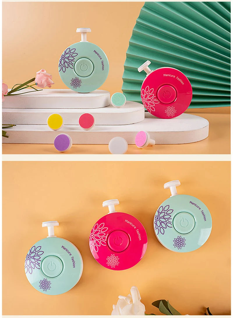 A pink electric baby nail trimmer is shown with various colored attachments on a light surface.