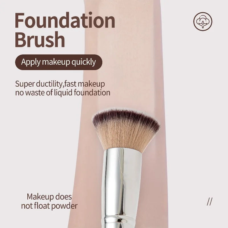 A close-up of a foundation brush with a silver ferrule and brown bristles shown against a light pink background.