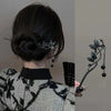 Accesorio de cabello negro con diseño de mariposa y detalles en plata y negro.