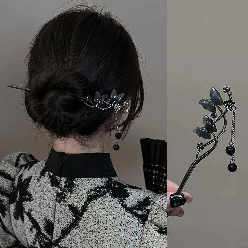 Accesorio de cabello negro con diseño de mariposa y detalles en plata y negro.