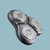 A close-up view of a gray triple blade electric shaver with three visible shaving heads.