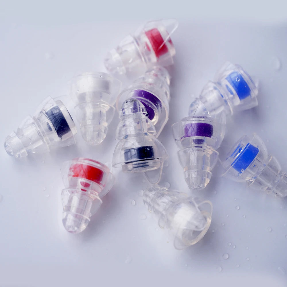 Several silicone earplugs in various colors including red, blue, and purple are shown scattered on a white surface.