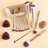 A collection of 13 professional makeup brushes in various sizes and shades displayed in a clear storage case.