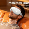 Ein Mann trägt einen weißen Augenmassierer und entspannt sich auf einer Couch beim Musikhören.