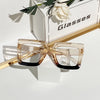Pair of classic square eyeglasses with clear lenses resting on a white box.