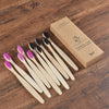 A box containing a set of ten natural bamboo toothbrushes is displayed on a wooden surface.