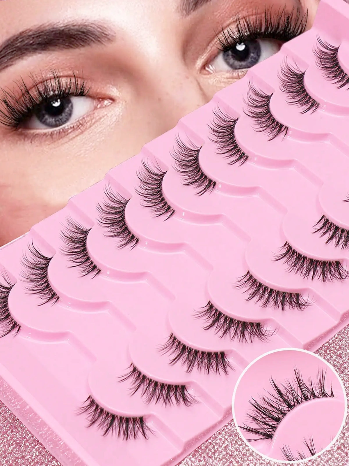 Rosa Plastikwimpernbehälter mit schwarzen Mink-Falschwimpern neben einem Augenlid einer Frau.