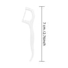 A white reusable dental floss pick with a handle and floss, shown next to a measurement scale.