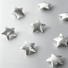 A collection of ten star-shaped hairpins with silver and gold finishes scattered on a light gray background.
