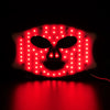 A professional red light therapy mask with numerous bright red LEDs illuminating a facial shape against a dark background.