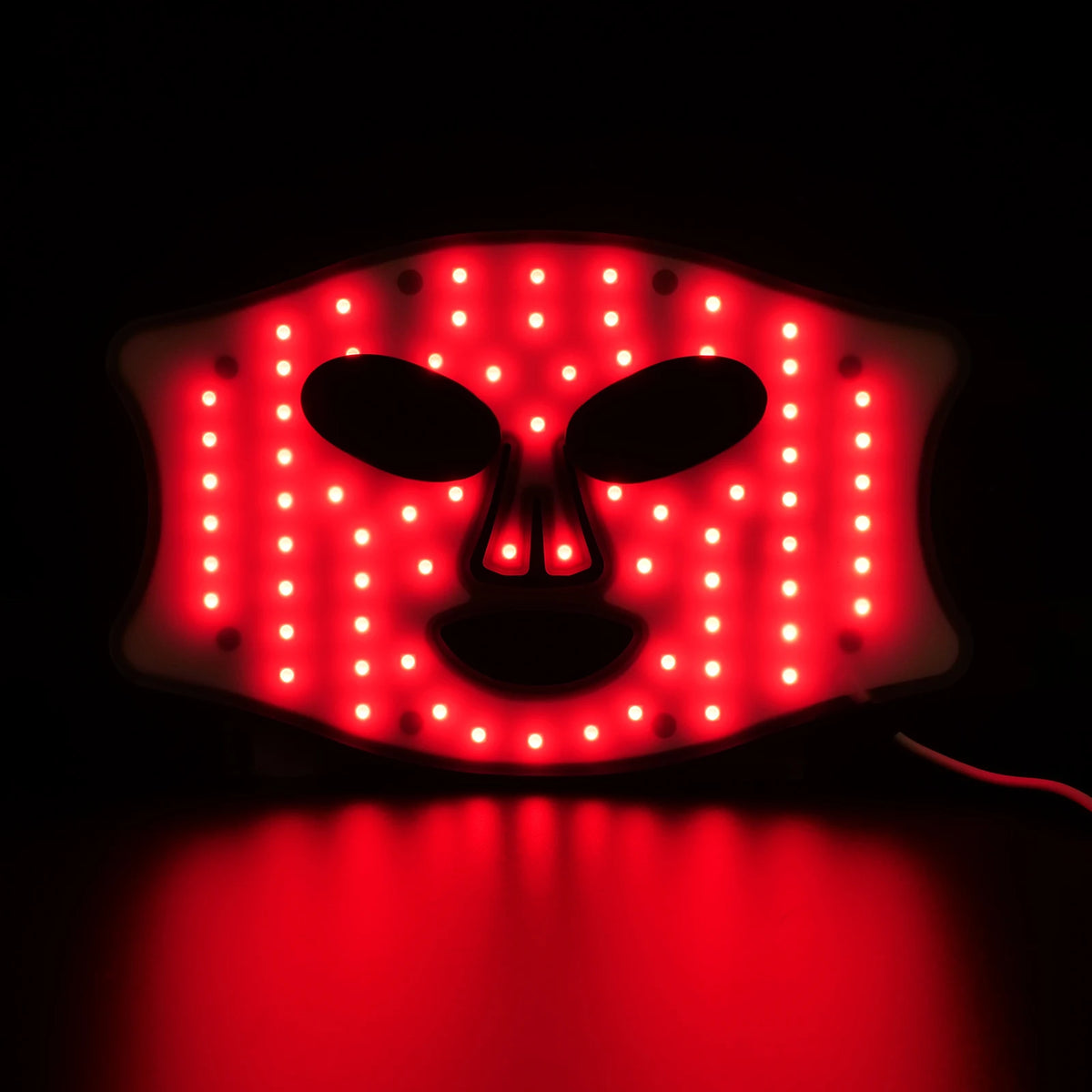 A professional red light therapy mask with numerous bright red LEDs illuminating a facial shape against a dark background.