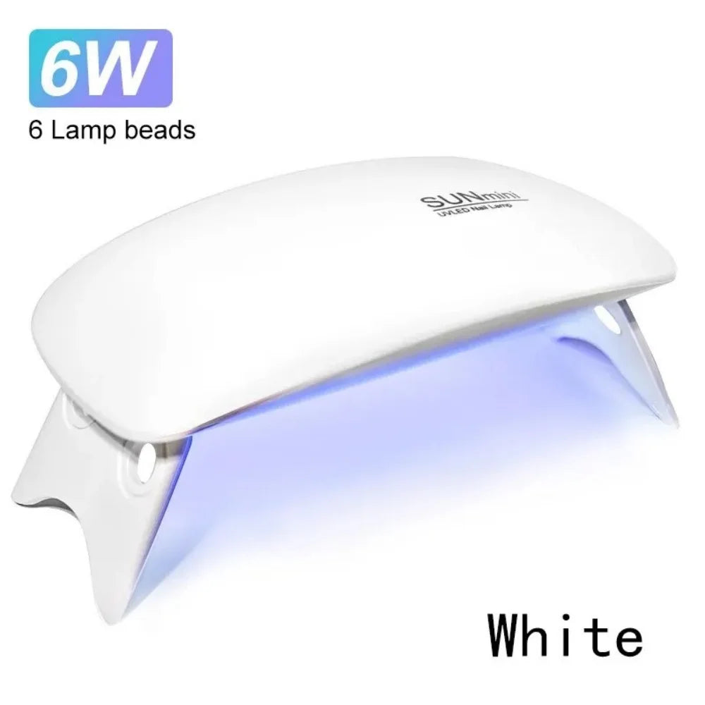 A white portable UV LED nail dryer lamp with six lamp beads shown illuminating a surface.