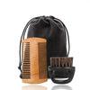 A set of boar bristle beard brush and comb in wood and black, packaged in a black drawstring bag.