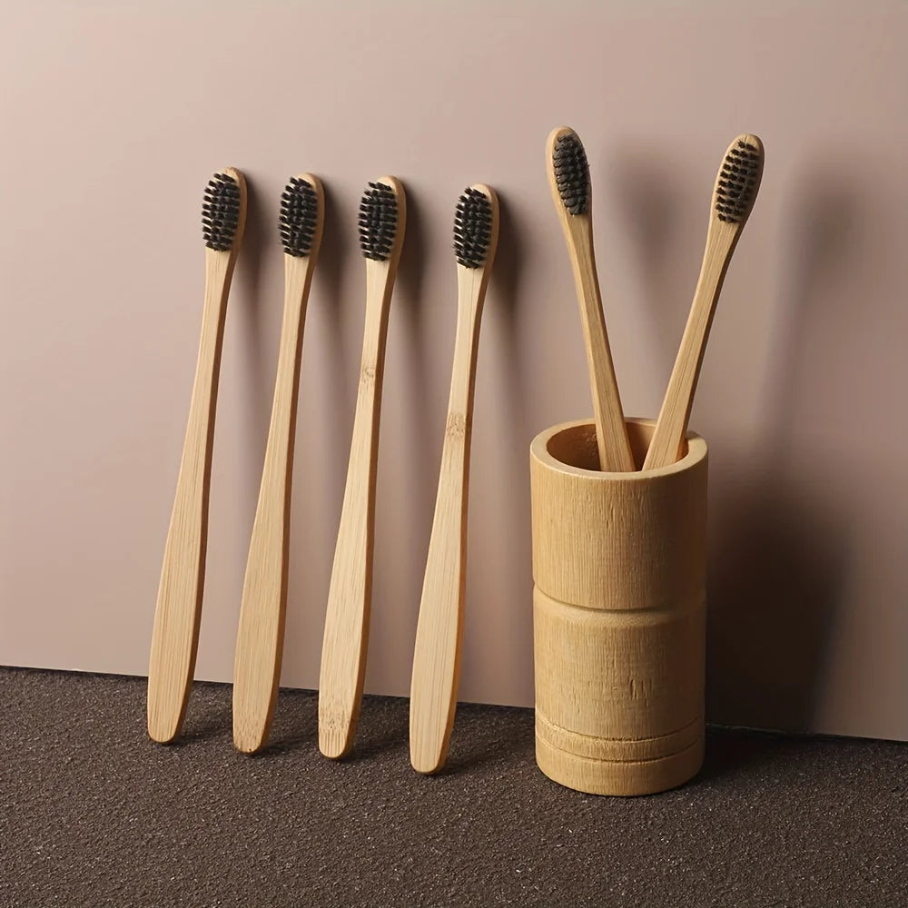 A set of six light wood bamboo toothbrushes with black bristles stored in a cylindrical holder.