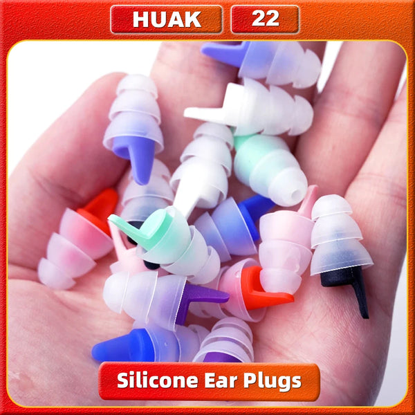 A hand holds various colored silicone earplugs for noise reduction.