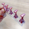Un ensemble de supports pour ongles magnétiques roses métalliques présentés dans un support en acrylique transparent.