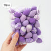 A hand holds a clear plastic bag filled with 50 reusable purple and white expandable makeup sponges.