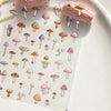 A sheet of watercolor mushroom nail art stickers featuring various sizes and colors of mushrooms on a white background.
