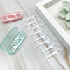 A set of white dental cleaning sticks and a pink plastic case are displayed on a marble surface.