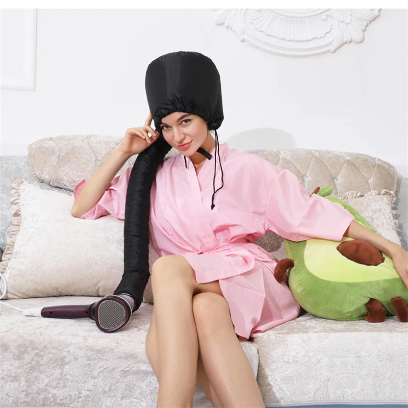 A woman wearing a black hair drying cap is sitting on a couch with a green stuffed animal.
