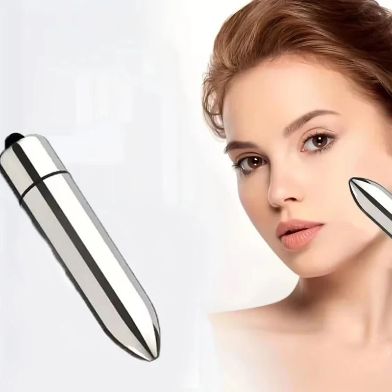 A woman is using a silver mini facial eye massager on her face.
